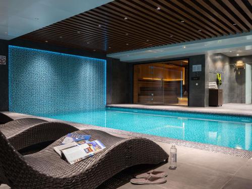a swimming pool with a wicker chair next to a table at Mövenpick Samarkand in Samarkand