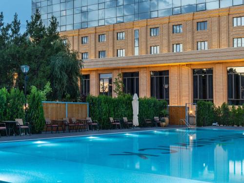 a large swimming pool in front of a building at Mövenpick Samarkand in Samarkand