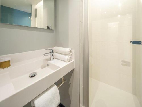 a white bathroom with a sink and a shower at ibis budget Forbach Centre in Forbach