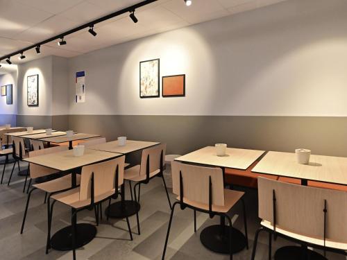a row of tables and chairs in a room at ibis budget Forbach Centre in Forbach