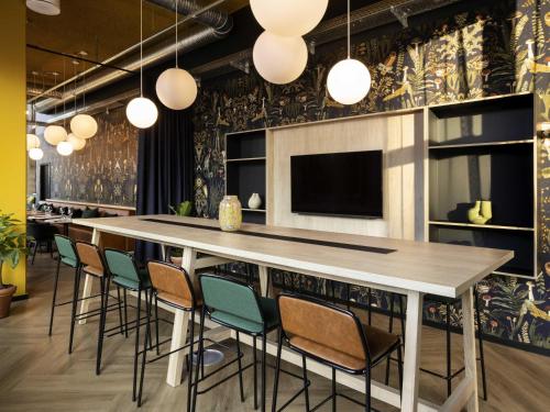 a bar in a room with chairs and a tv at ibis Styles Copenhagen Orestad in Copenhagen
