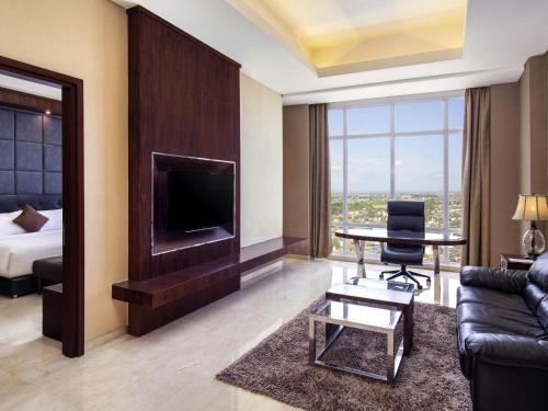 a living room with a couch and a tv and a bed at Grand Mercure Solo Baru in Solo