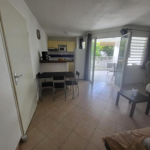 a living room with a table and chairs and a kitchen at Appartement Personnes à Mobilité Réduite in Sainte-Anne