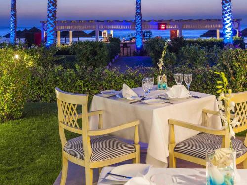 a table with two chairs and a table with wine glasses at Rixos Sharm El Sheikh - Adults Only 18 Plus in Sharm El Sheikh