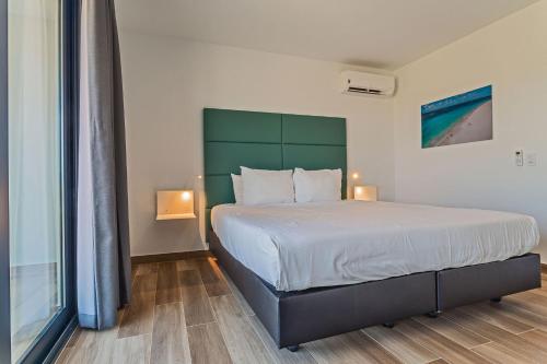 a bedroom with a large bed with a green headboard at Tuscany Residence Aruba in Palm-Eagle Beach