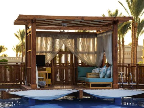 a pavilion with a couch and a television in a pool at Rixos Sharm El Sheikh - Adults Only 18 Plus in Sharm El Sheikh