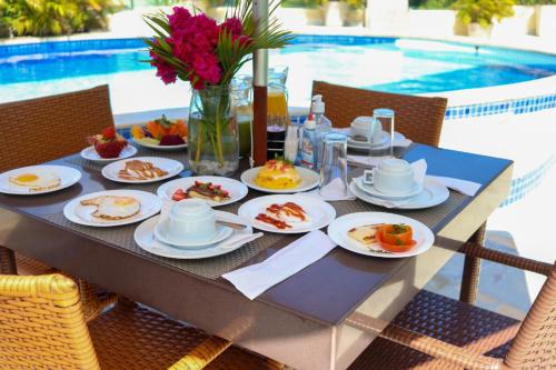 a table with plates of food on it next to a pool at Star Hotel in Jericoacoara
