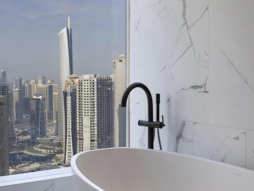 a bath tub in a bathroom with a city view at SO/ Uptown Dubai in Dubai