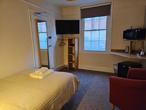 a bedroom with a bed and a tv and two windows at Edward Hotel in Gloucester