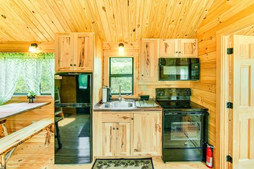 a kitchen with wooden cabinets and a sink and a stove at 5 Mi to Susquehanna Boating! Secluded Log Cabin in Shamokin Dam