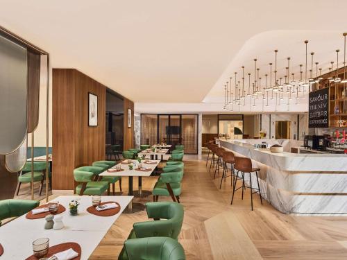 un ristorante con sedie e tavoli verdi e un bar di Novotel Mumbai International Airport a Mumbai