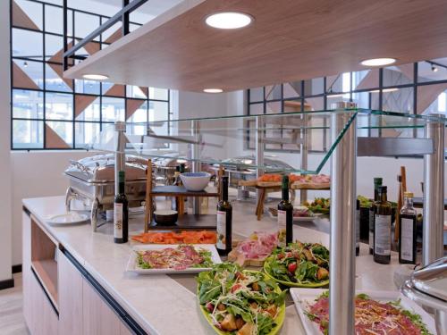 a buffet with many plates of food on a counter at Fora Hotel Hannover by Mercure in Hannover
