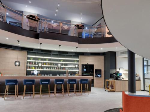 a restaurant with a bar with blue stools at Fora Hotel Hannover by Mercure in Hannover