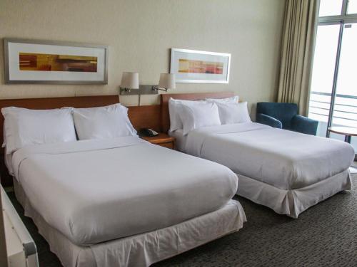a hotel room with two beds and a chair at Novotel Puerto Montt in Puerto Montt