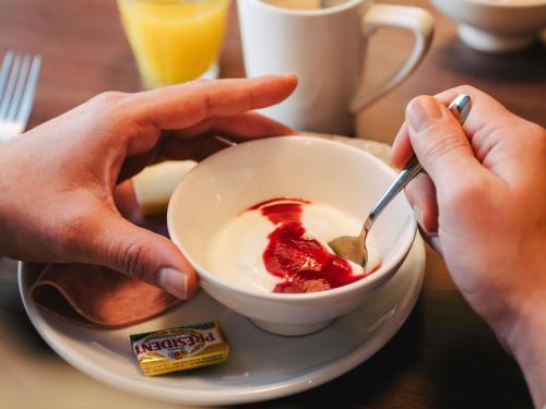 a person eating a bowl of food with a spoon at Ibis Rouen Centre Rive Gauche Mermoz in Rouen