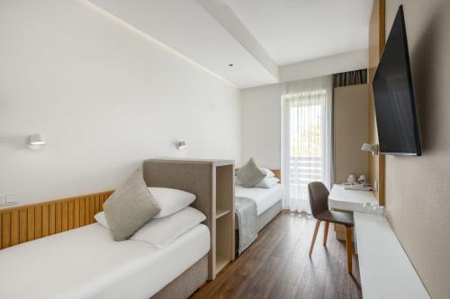 a hotel room with two beds and a desk at Cardoner Hotel és Konferenciaközpont in Dobogoko