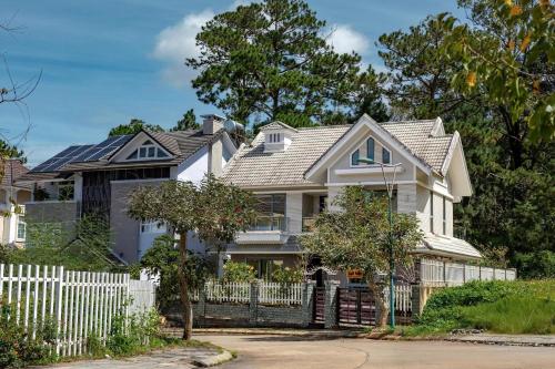 une maison blanche avec une clôture blanche dans l'établissement Luxury Golf Valley Villa Đà Lạt, à Đà Lạt