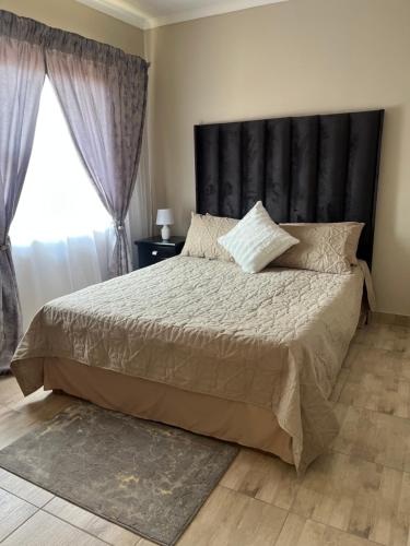 a bedroom with a large bed with a black headboard at Modern Style Apartments, An Escape From The City in Pretoria