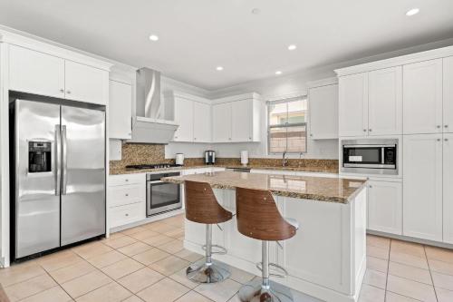FrancesにあるStylish 3BR Irvine Oasis Family Friendly w Garageの白いキャビネットとステンレス製の電化製品を備えたキッチン