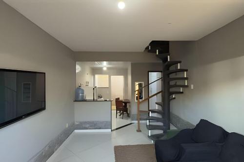 a living room with a spiral staircase and a television at Duplex em Itaúna 4min da Praia que ocorre o WSL, 1min da pista de skate do LS, pracinha com parque infantil, quadra de futebol, tudo isso a 1 min da duplex, perto do comércio, wi-fi super rápido, estacionamento gratuito, monitoramento 24hrs in Saquarema