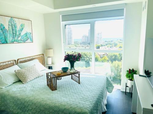 a bedroom with a bed and a table with flowers on it at Lakeview Steps to the lake & just minutes to downtown in Toronto