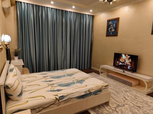 a bedroom with a bed and a flat screen tv at Двухкомнатная квартира студия in Almaty