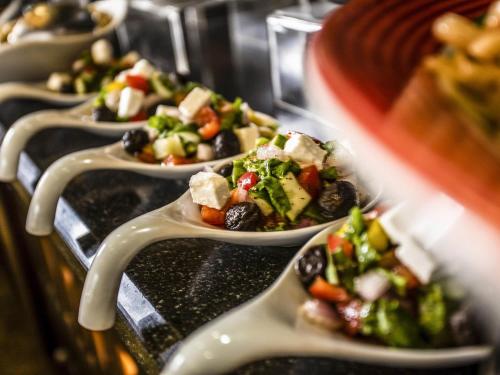 a row of plates of food on a buffet at Mövenpick Hotel Ikoyi Lagos in Lagos