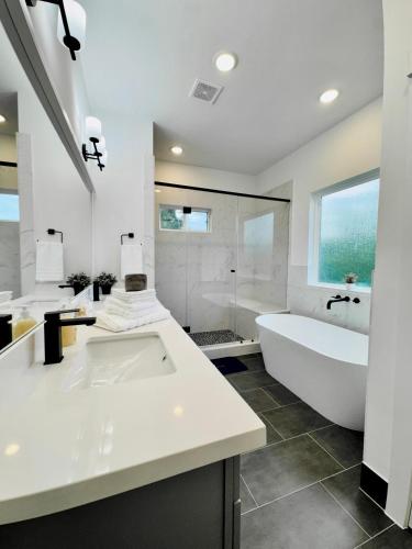 a white bathroom with a tub and a sink and a bath tub at Colorful Dining Experience in Cozy Getaway in Houston
