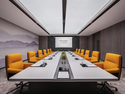 a conference room with a long table and yellow chairs at Novotel Kunshan Yangcheng Lake in Kunshan