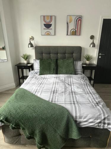 a bedroom with a bed with a green and white comforter at 1st Floor 1 Bed Studio in Weston-super-Mare