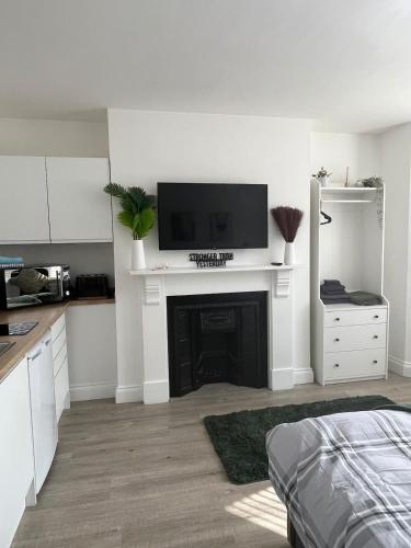 a white room with a fireplace with a tv on top at 1st Floor 1 Bed Studio in Weston-super-Mare