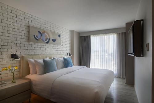 a bedroom with a large white bed and a brick wall at Shama Yen-Akat Bangkok in Bangkok