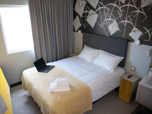 a hotel room with a bed with a laptop on it at ibis Styles Antofagasta in Antofagasta