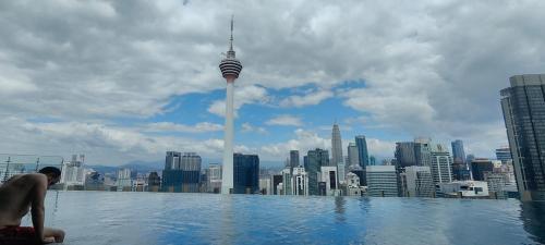 einem Mann, der in einem Infinity-Pool mit Blick auf eine Stadt sitzt in der Unterkunft Ceylonz Suites, Bukit Bintang, Kuala Lumpur in Kuala Lumpur
