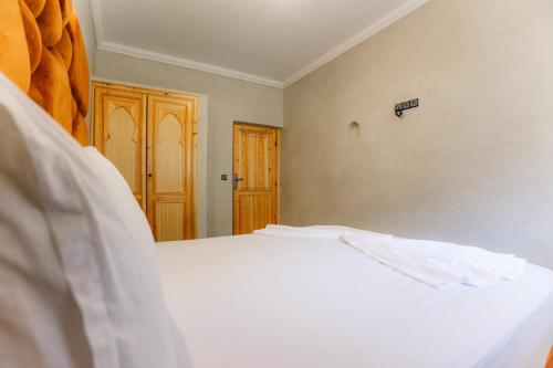 a bedroom with a white bed and a wooden door at The best apartments of Ourika valley in Amlouggui