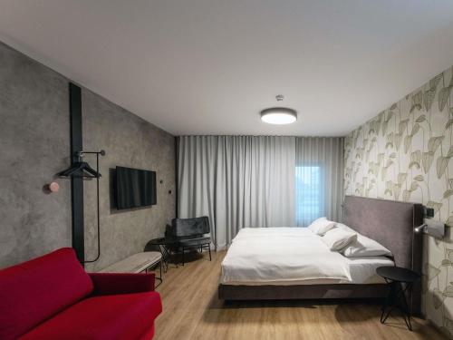 a bedroom with a bed and a red couch at ibis Styles Ljubljana Centre in Ljubljana