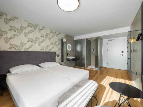 a bedroom with a large white bed and a chair at ibis Styles Ljubljana Centre in Ljubljana