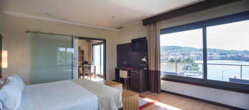 a hotel room with a bed and a large window at Gran Talaso Hotel Sanxenxo in Sanxenxo