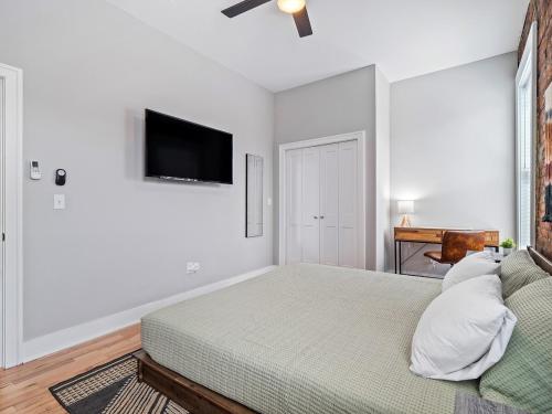 a white bedroom with a bed and a flat screen tv at Stunning Boho Apt in Ohio City in Cleveland