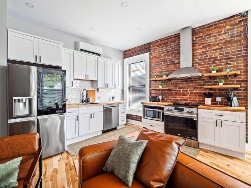 a kitchen with white cabinets and a brick wall at Stunning Boho Apt in Ohio City in Cleveland