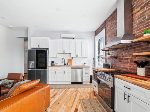 a kitchen with white cabinets and a brick wall at Stunning Boho Apt in Ohio City in Cleveland