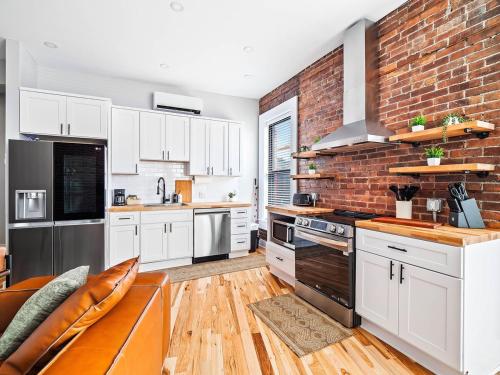 a kitchen with white cabinets and a brick wall at Stunning Boho Apt in Ohio City in Cleveland