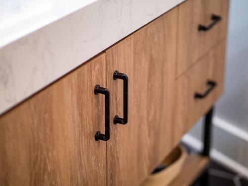 a wooden cabinet with black handles in a bathroom at Stunning Boho Apt in Ohio City in Cleveland