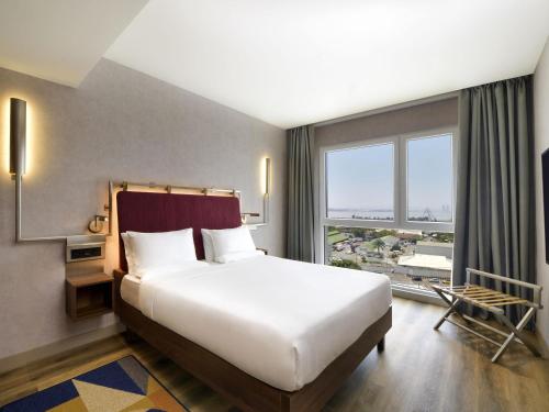 a bedroom with a large bed and a large window at Novotel Kinshasa La Gombe in Kinshasa
