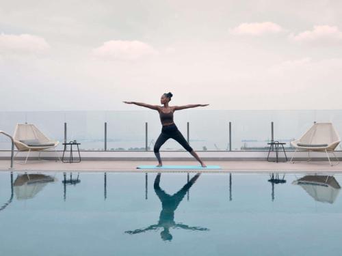 a woman standing on a surfboard next to a swimming pool at Novotel Kinshasa La Gombe in Kinshasa