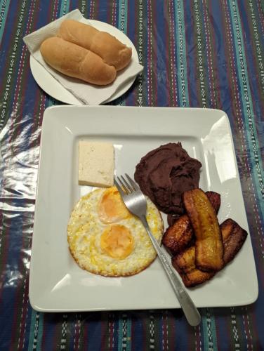 Un plato de desayuno con huevos, salchichas y pan. en Hotel Bluehouse, en Guatemala
