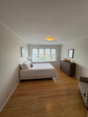 a white bedroom with a bed and a couch at Airport Manor Unit 4, 2 Bedroom Apartment in Torbay