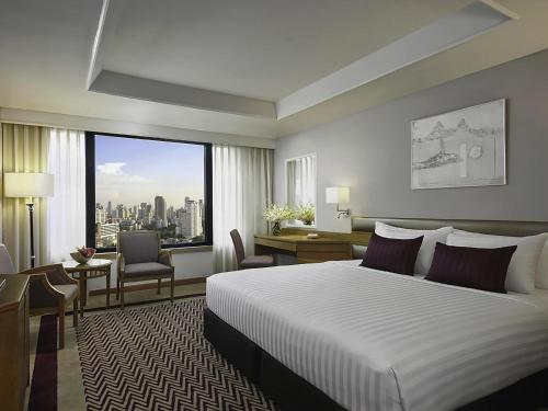 a hotel room with a bed and a large window at Grand Mercure Bangkok Atrium in Bangkok