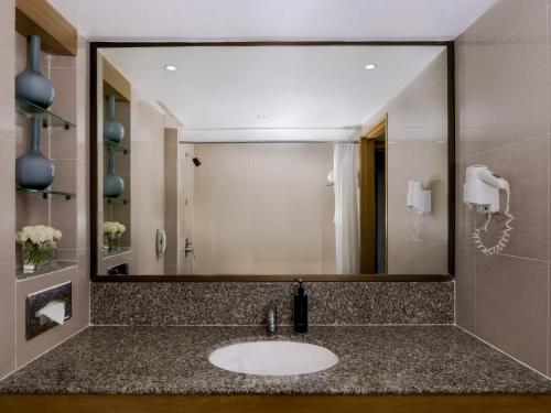 a bathroom with a sink and a large mirror at Grand Mercure Bangkok Atrium in Bangkok