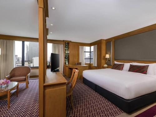 a hotel room with a bed and a desk at Grand Mercure Bangkok Atrium in Bangkok